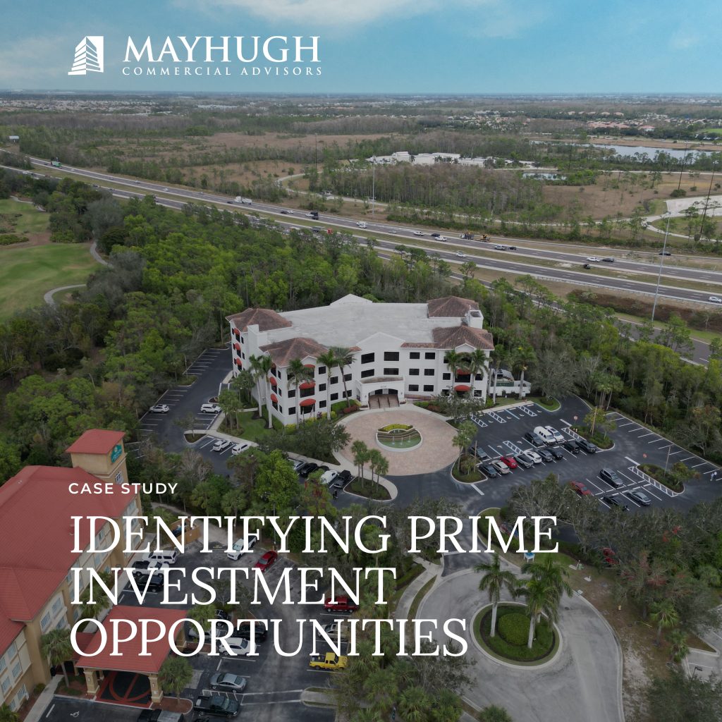 Aerial view of a commercial office building with surrounding parking lot and landscaping, featuring the Mayhugh Commercial Advisors logo and the text "Identifying Prime Investment Opportunities.