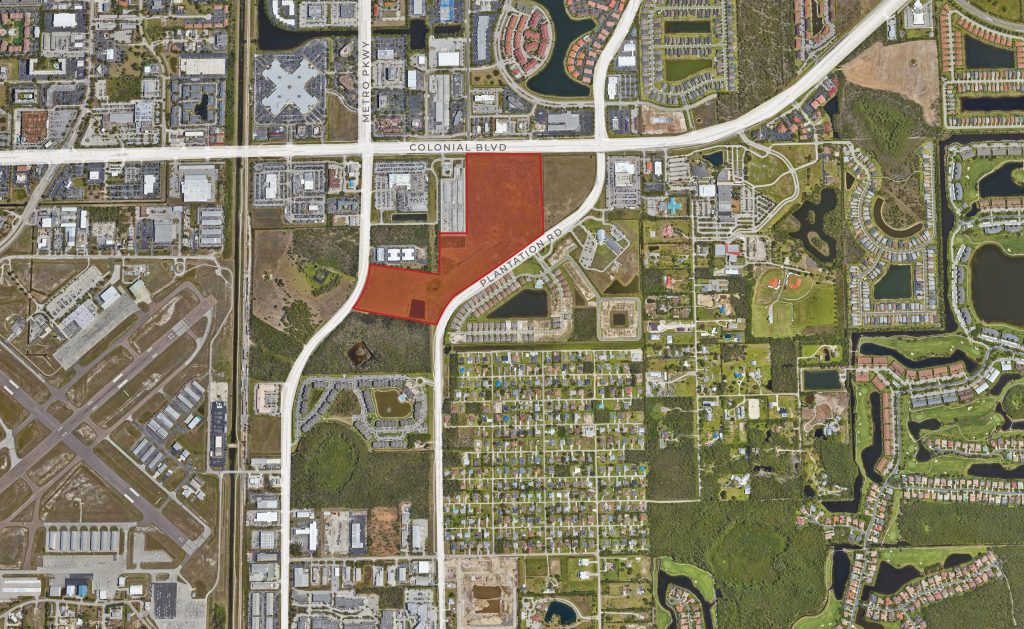 Aerial view of an urban area with roads, buildings, neighborhoods, and a marked red zone near the intersection of Colonial Blvd and Metro Parkway. An airport is visible on the left.