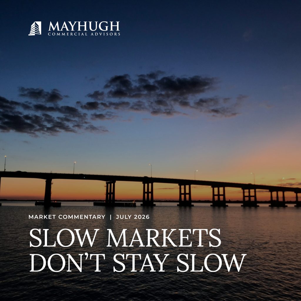 A bridge spans across water at sunset with the text, "Slow Markets Don’t Stay Slow" and "Mayhugh Commercial Advisors.