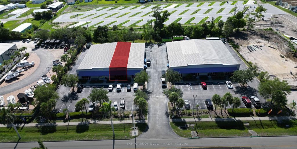 Aerial view of two adjacent commercial buildings with parking lots; one unit in the left building is highlighted in red.